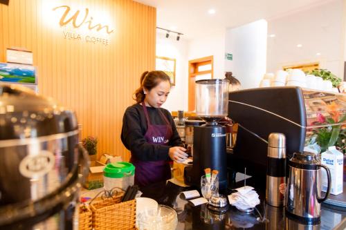 a woman standing behind a counter with a blender at Win Villa Coffee in Da Lat