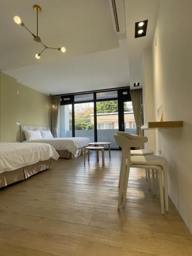 una camera da letto con due letti, un tavolo e una sedia di Love Vacation Pourquoi pas a Città di Hualien