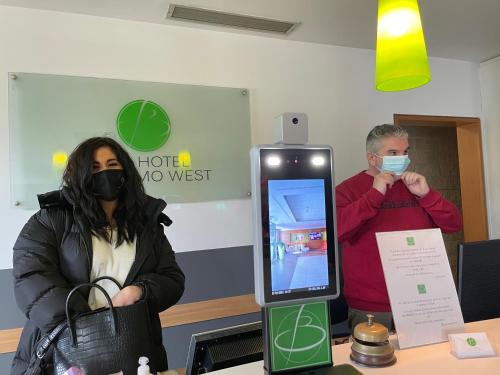 a man and a woman wearing face masks next to a kiosk at Bes Hotel Bergamo Ovest in Mozzo