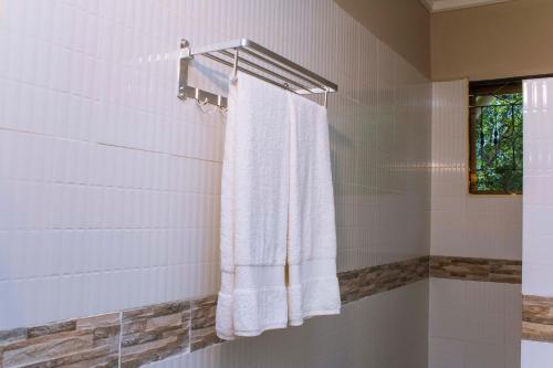 a bathroom with a white towel hanging in a shower at MANTIS LODGE & CAMPING SITE in Morogoro
