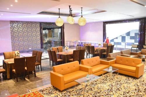 a restaurant with orange couches and tables and chairs at THE GRAND VILLAGE in Morādābād