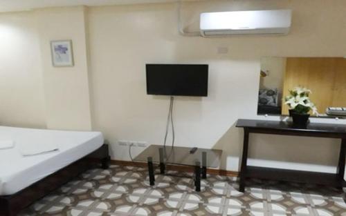 a room with a bed and a tv on the wall at WMV Hotel & Restaurant in Infanta