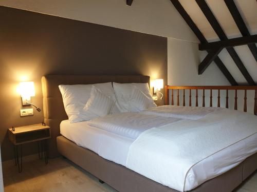 a bedroom with a large white bed with two lamps at Appartement Am Hohenbusch in Burg-Reuland