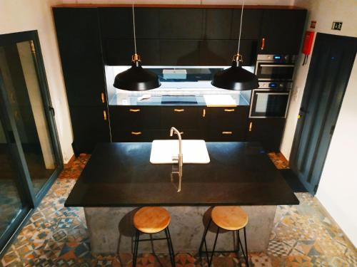 a kitchen with a black counter top and two stools at Janela do Porto in Prainha de Baixo