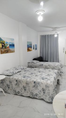 dwa łóżka w białym pokoju z dwoma łóżkami w obiekcie Quitinete Centro de Guarapari. w mieście Guarapari