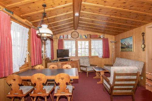salon ze stołem, krzesłami i kanapą w obiekcie Chalet Iris w mieście Adelboden