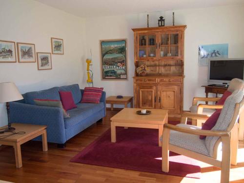 a living room with a blue couch and a tv at Ferienwohnung Bim Stei in Adelboden
