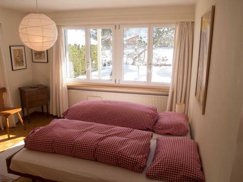 a bedroom with a bed with red pillows and a window at Ferienwohnung Bim Stei in Adelboden