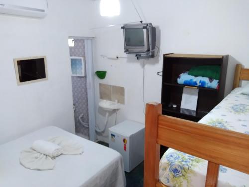a room with two beds and a tv on a wall at Chapada Casas da Izete in Lençóis