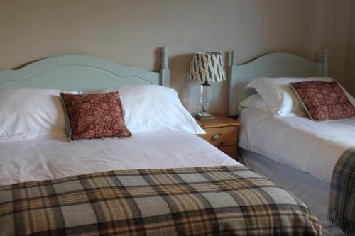 a bedroom with two beds and a lamp on a night stand at Heatherbank Guest House in Strontian