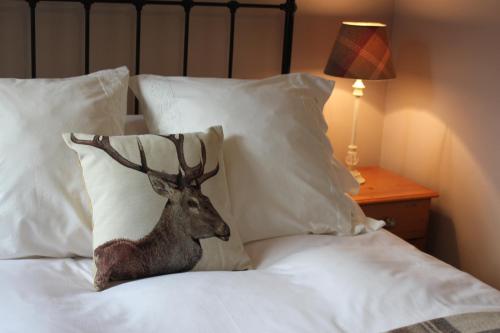 a statue of a deer on a bed with pillows at Heatherbank Guest House in Strontian