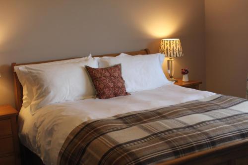 
a bed with a white comforter and pillows at Heatherbank Guest House in Strontian
