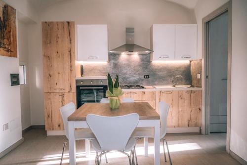 een keuken met een houten tafel en witte stoelen bij Appartamento Mare in La Caletta