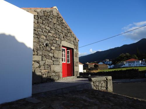 a red door on a stone building with mountains in the background at Janela do Porto in Prainha de Baixo