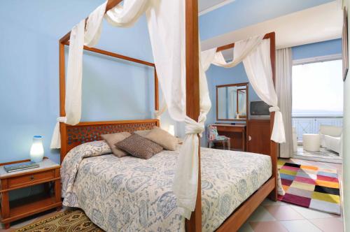 a bedroom with a canopy bed with white curtains at Akti in Nafpaktos