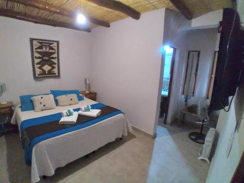 a bedroom with a bed with blue and white sheets at Los Agustinos in Purmamarca