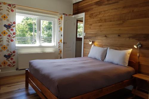 a bedroom with a bed and a window at Hostal Compass del Sur in Puerto Varas