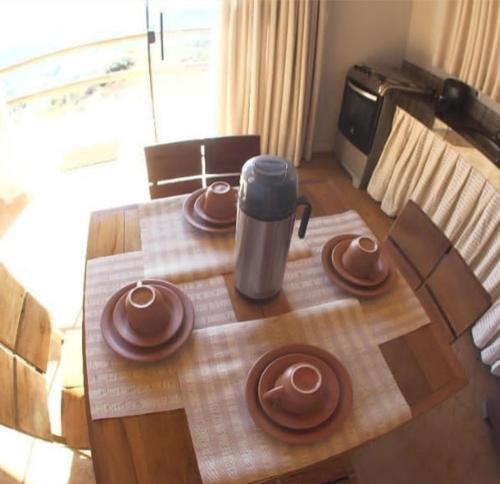 a wooden table with plates and a coffee pot on it at Chalés Beija-flor in Itambé do Mato Dentro