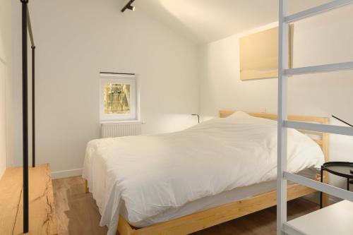 een slaapkamer met een bed met witte lakens en een ladder bij Houtsaegertje in De Panne