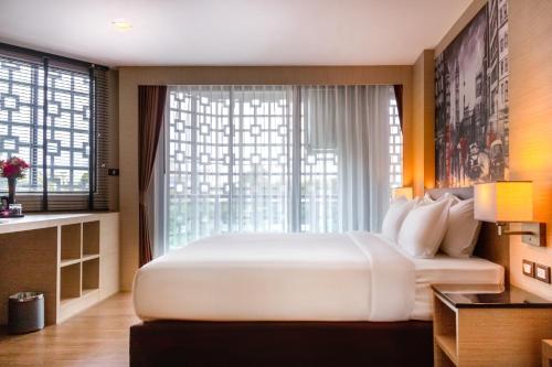 a large white bed in a room with a window at GLOW Pattaya in Pattaya South