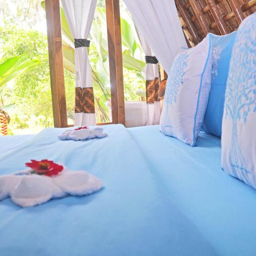 a blue bed with two towels on top of it at Lagoona Beach Bungalows - Eco Bungalows Batukaras in Batukaras