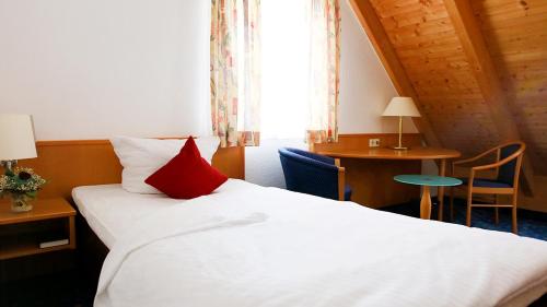 ウルムにあるホテル ガストホフ アドラーの赤い枕付きのベッドが備わるホテルルームです。
