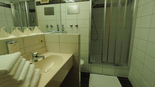 a bathroom with a sink and a shower with mirrors at Hotel Gasthof Adler in Ulm