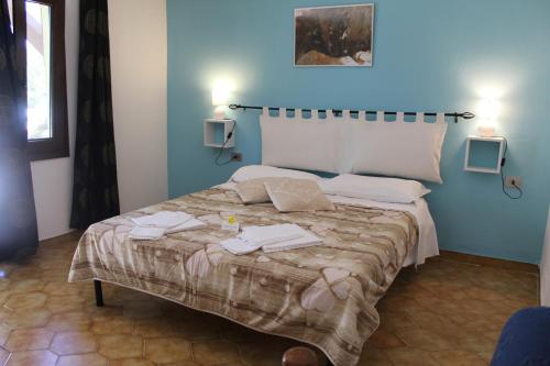 ein blaues Schlafzimmer mit einem Bett mit Handtüchern darauf in der Unterkunft Agriturismo Pira Pinta in Dorgali