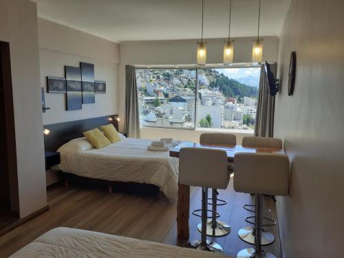 Bariloche Home Suites في سان كارلوس دي باريلوتشي: غرفة نوم بسرير وطاولة ونافذة