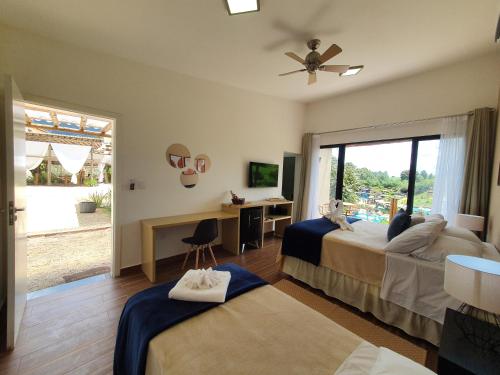a bedroom with two beds and a desk and a window at Ganso Complexo de Lazer in Lambari