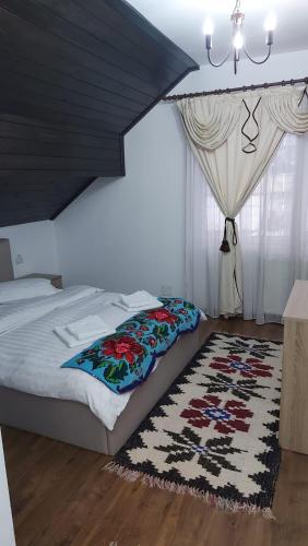 a bedroom with a bed with a rug and a chandelier at Casa MYM in Moisei