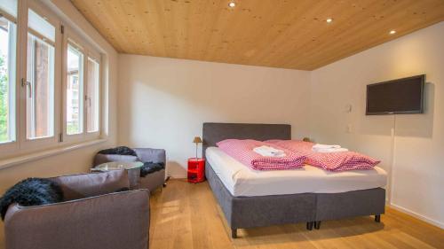 a bedroom with a bed and two chairs and a television at Studio Riseten in Adelboden
