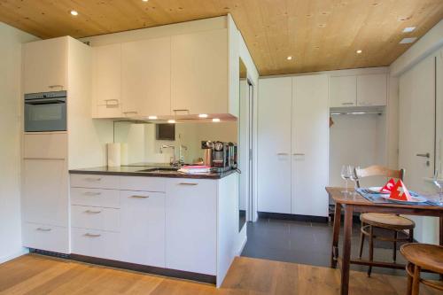 eine Küche mit weißen Schränken und einem Holztisch in der Unterkunft Studio Riseten in Adelboden