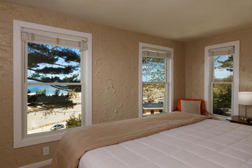 a bedroom with a large bed and two windows at Looking Glass Beachfront Inn in Grand Haven