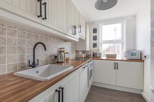 a white kitchen with a sink and a window at La casetta d'Àneu in Oxford