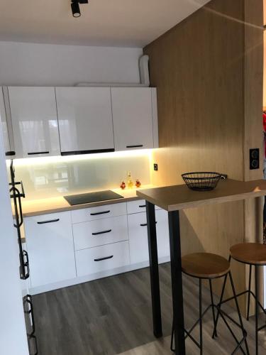 a kitchen with white cabinets and a table and stools at Apartament na Skrzypka in Cieszyn