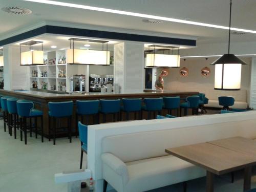 a restaurant with a bar with blue chairs at Hotel Bahía in Santander