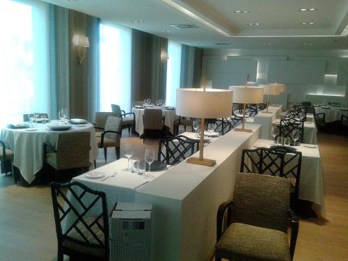 a dining room with tables and chairs and lamps at Hotel Bahía in Santander