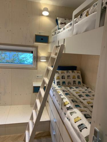 um beliche num pequeno quarto com uma escada em WAD NOU Terschelling heerlijk duurzaam chalet! em Midsland