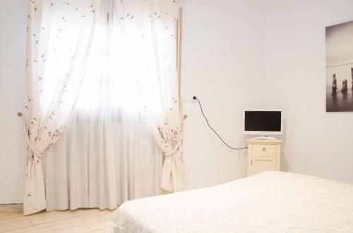 a bedroom with white curtains and a bed and a television at Hotel Algete in Algete