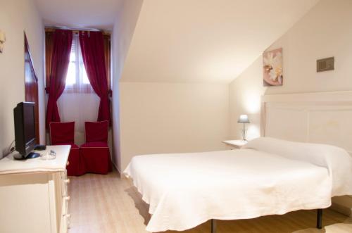 a bedroom with a white bed and a television at Hotel Algete in Algete