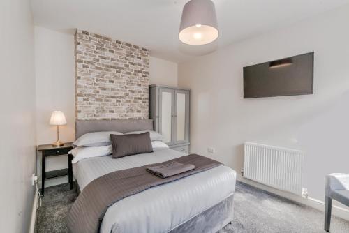 a bedroom with a bed and a brick wall at Cannock Hotel Apartments in Cannock