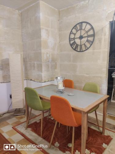 a table and chairs with a clock on a wall at Semi-basement, cosy apartment interconnected to our residence a traditional Maltese townhouse in Senglea