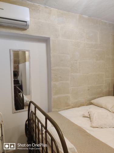 a bedroom with a bed and a mirror at Semi-basement, cosy apartment interconnected to our residence a traditional Maltese townhouse in Senglea