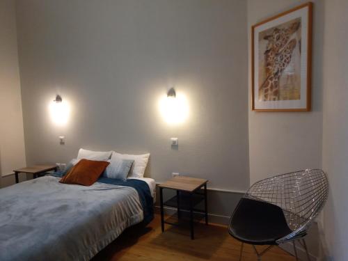 - une chambre avec un lit, une chaise et deux lumières dans l'établissement Centre gare, à Saint-Dié-des-Vosges