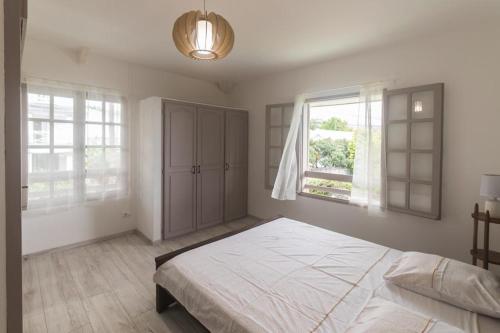 a bedroom with a large bed and two windows at appartement 1 avec wifi in Ravine des Cabris
