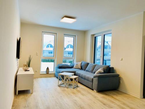 a living room with a blue couch and windows at Haus Meerruhe Karlshagen Apartment 1-6 in Ostseebad Karlshagen