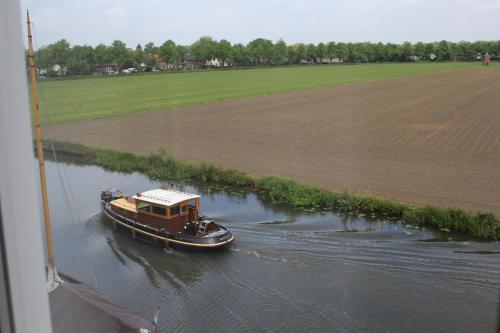 a boat traveling down a river next to a field at Het Wapen van Harmelen in Harmelen