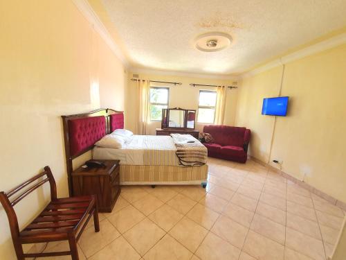 a bedroom with a bed and a red couch at The Palace Guest House in Harare