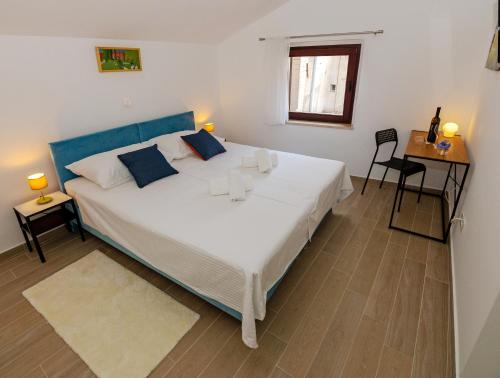 Un dormitorio con una gran cama blanca y una mesa en B&B Rooms Old Town Rab en Rab